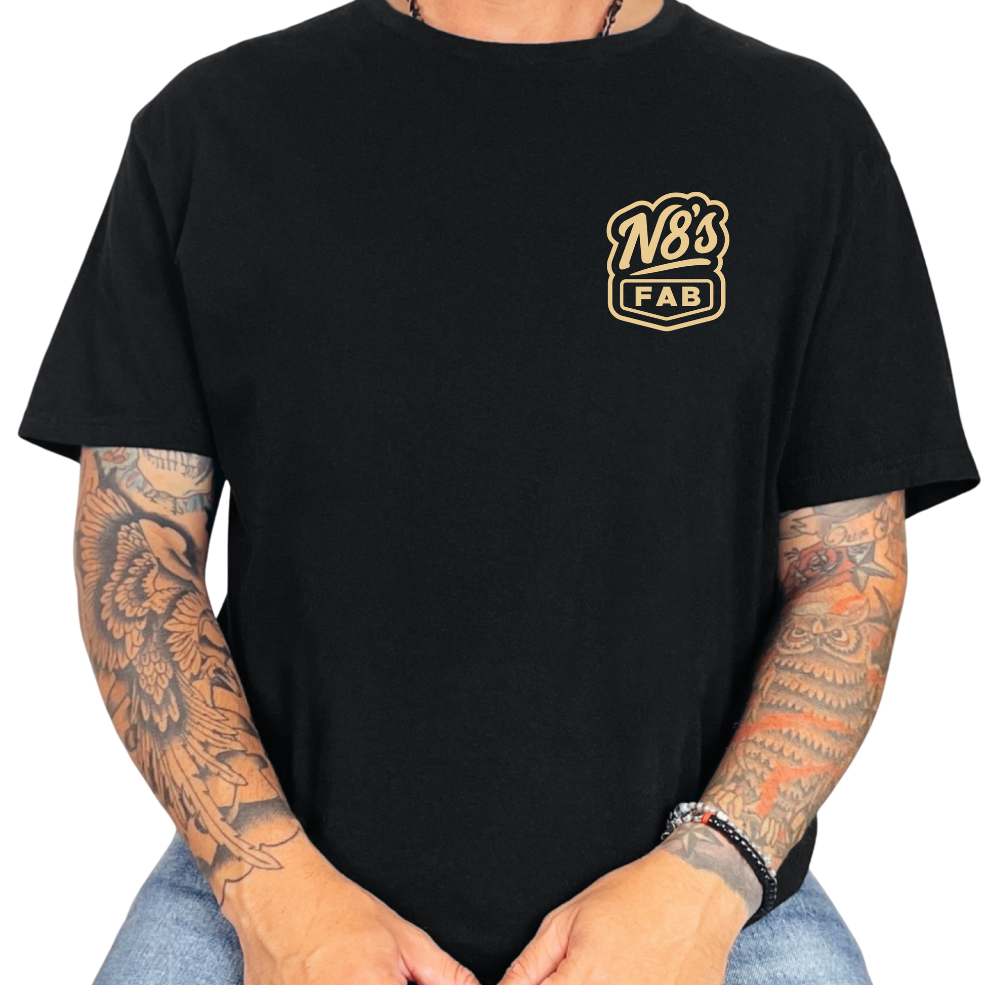 Black unisex t-shirt with gold logo worn by a person with tattoos